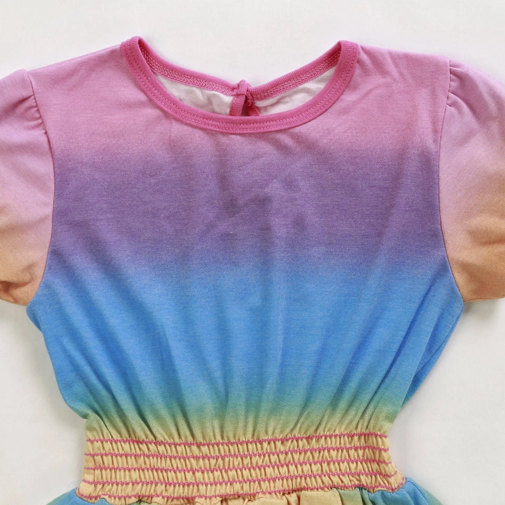 Close-up of the rainbow dress bodice showing the ombré gradient and pink smocked waistband