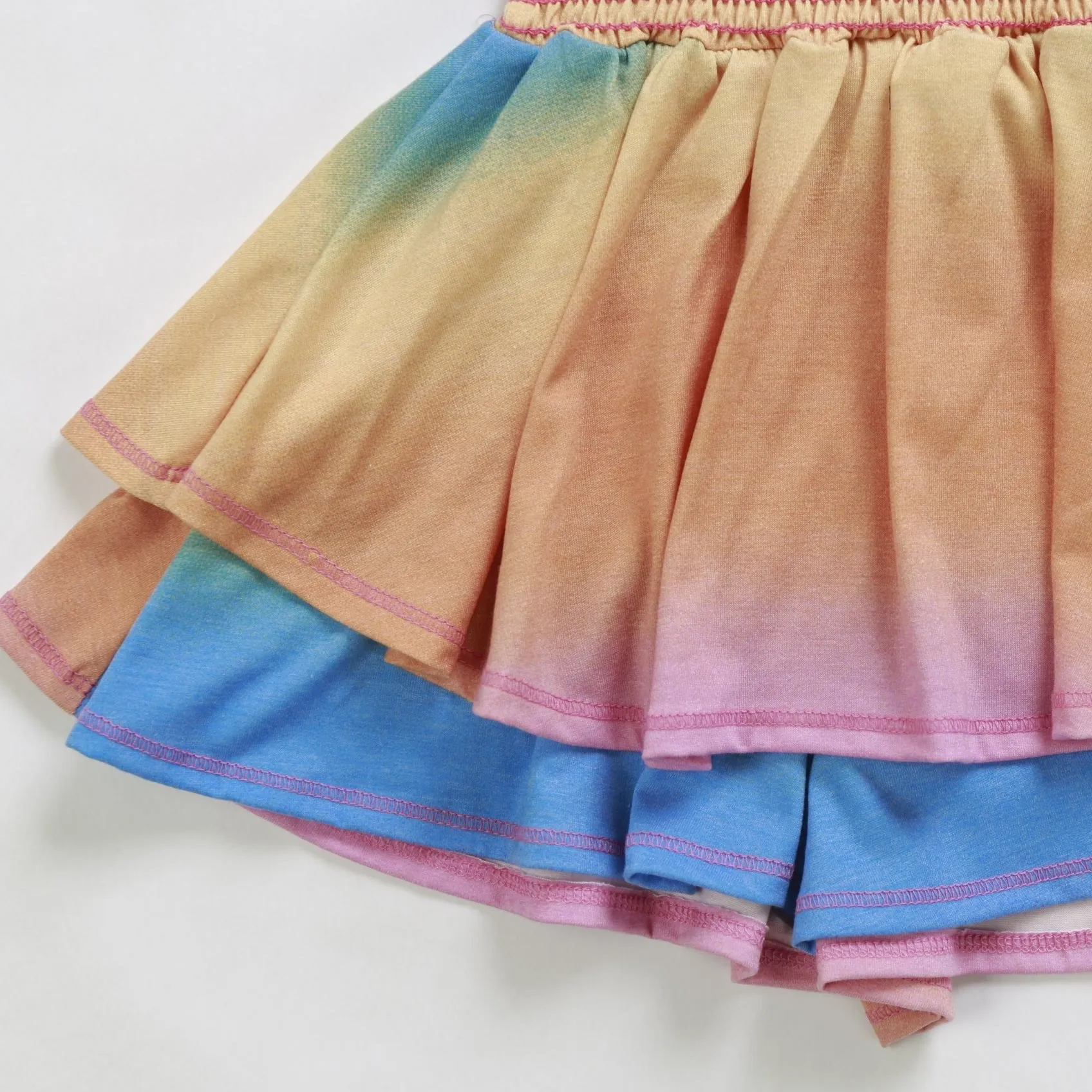 Close-up of the rainbow dress tiered skirt layers with pink overlock stitching
