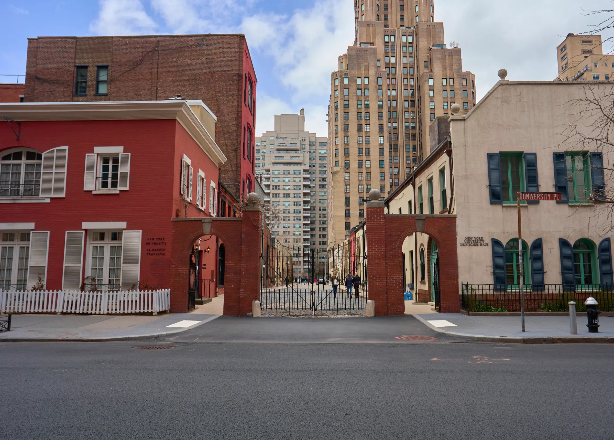 Gated mews framed by red and cream townhouses against Manhattan high-rises