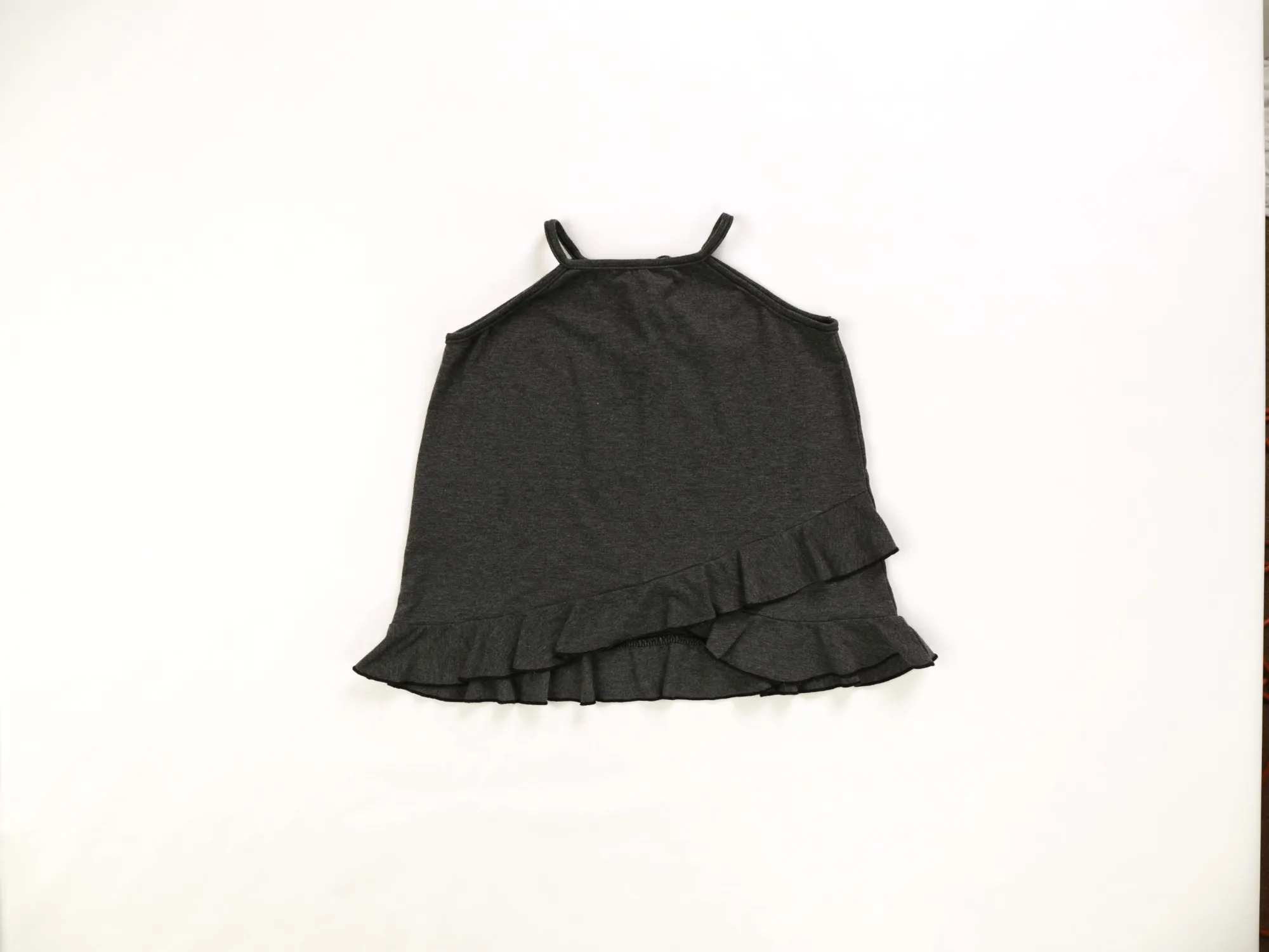 Charcoal ruffle-hem tank on white paper, shot from overhead before editing